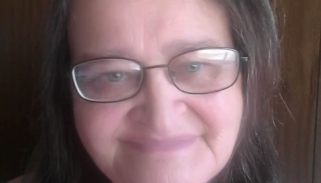 Close-up portrait of a woman with dark hair and glasses smiling gently.