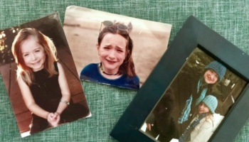 Three family pictures showing a girl at different ages, one in a black frame, resting on green fabric.