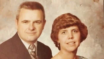 Vintage studio portrait of a man in a suit and tie beside a smiling woman with short brown hair.