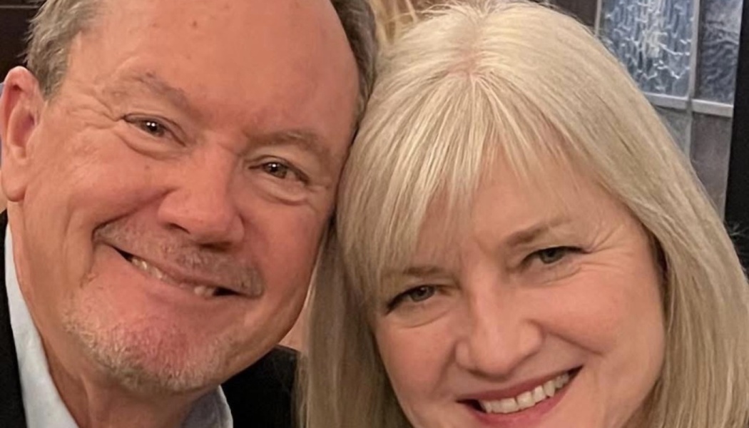 Close-up of a smiling man and blonde woman resting their heads together lovingly.