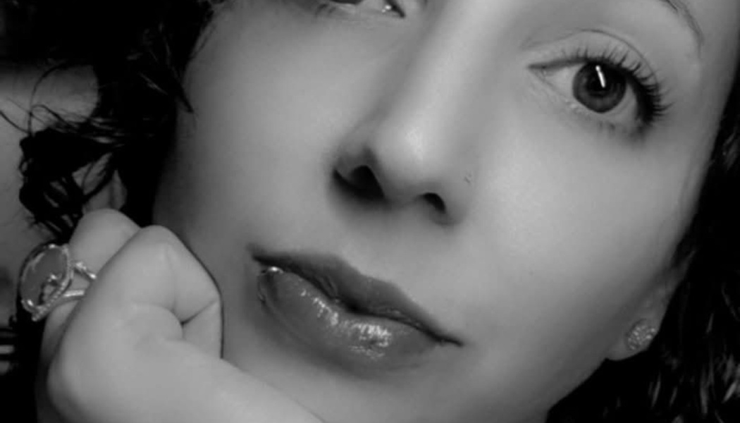 Black and white close-up portrait of a woman resting her chin on her hand with a thoughtful expression.