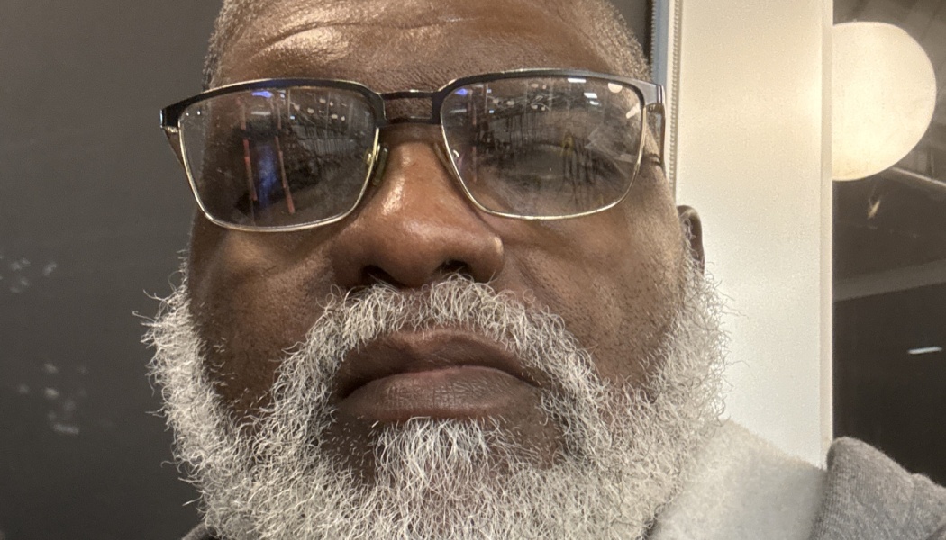 Close-up portrait of a mature Black man with glasses and a full, thick white beard.