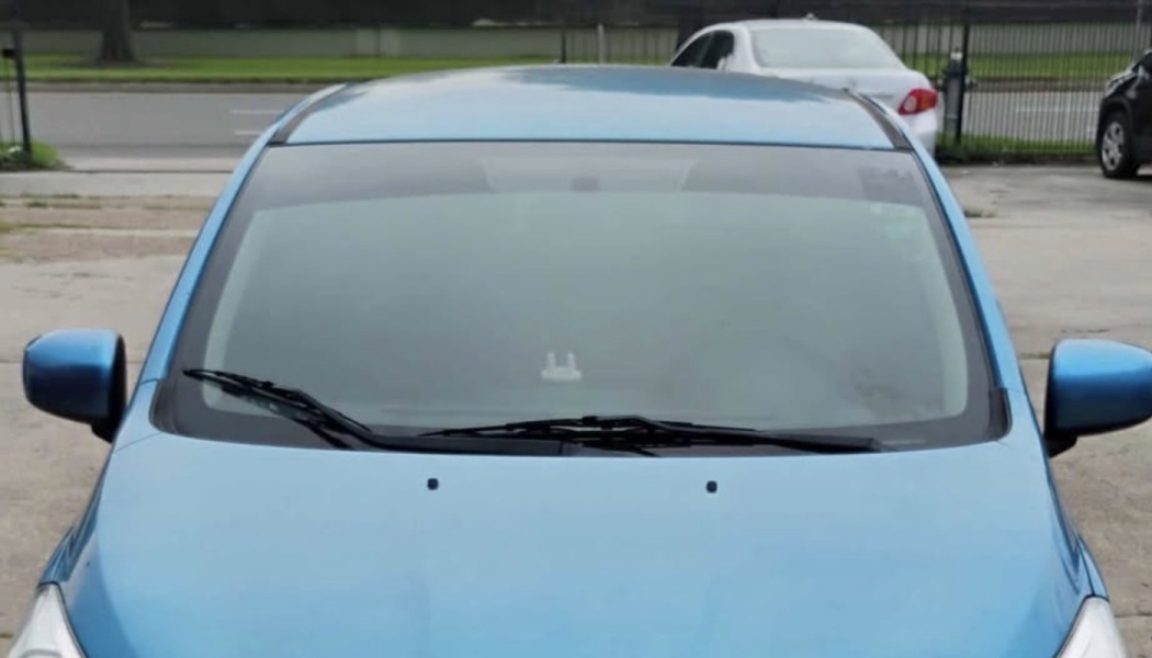 Front view of a light blue car showing its windshield, hood, and side mirrors.