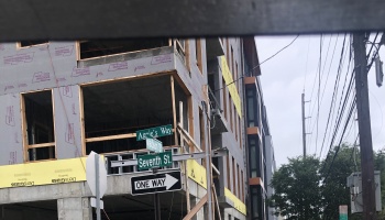 Multi-story building under construction behind street signs for Aggie's Way and Seventh St.