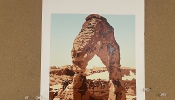 Graphic art print of Delicate Arch in Utah, pinned to a corkboard.