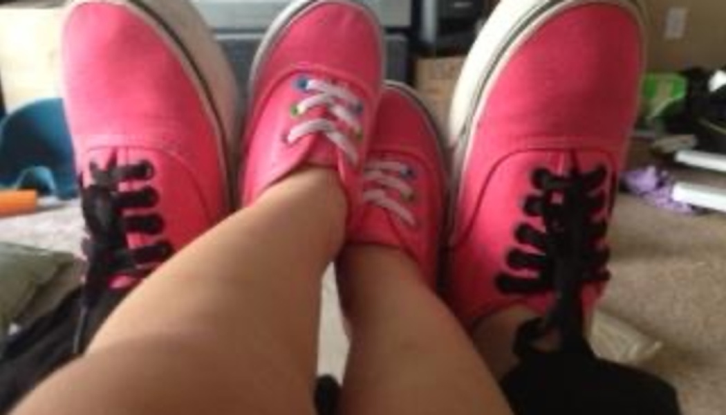 Matching bright pink canvas sneakers worn by an adult and a child side by side.