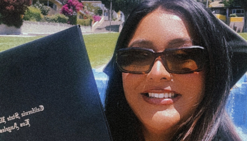 Smiling graduate in sunglasses and cap holding a California State University, Los Angeles diploma folder.