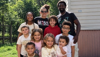 A smiling family with two parents and eight children posing together outdoors.