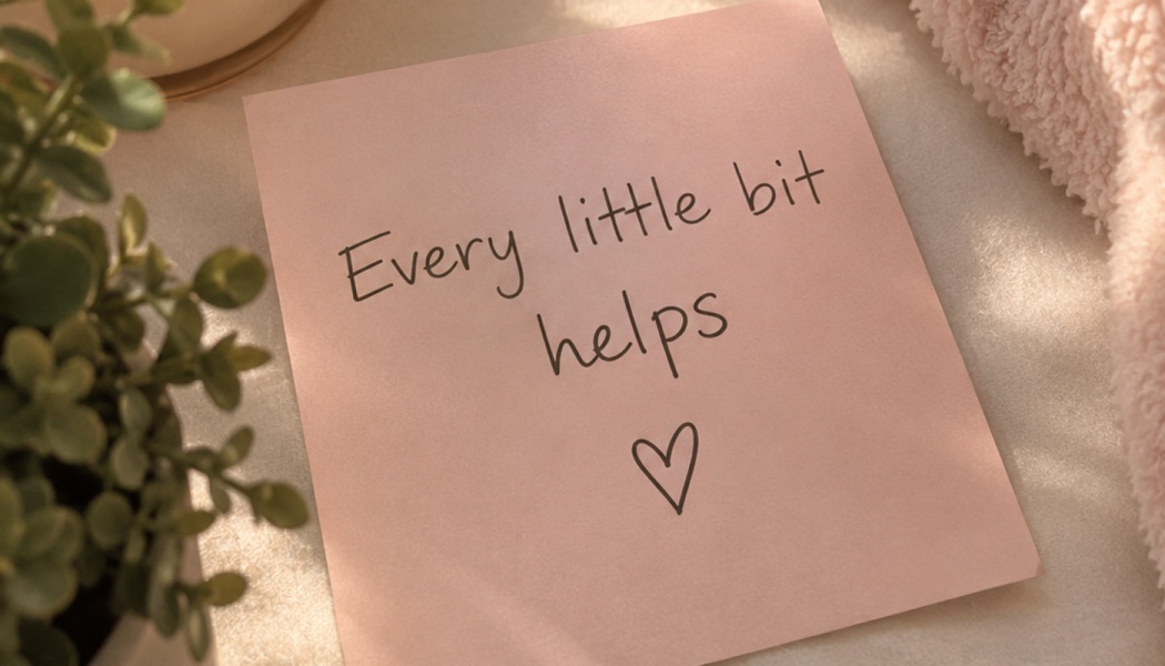 Pink note with handwritten text "Every little bit helps" and a drawn heart symbol, placed next to a plant.