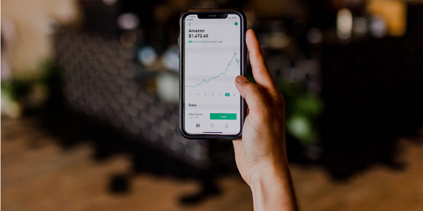 hand with a phone showing investment in a company