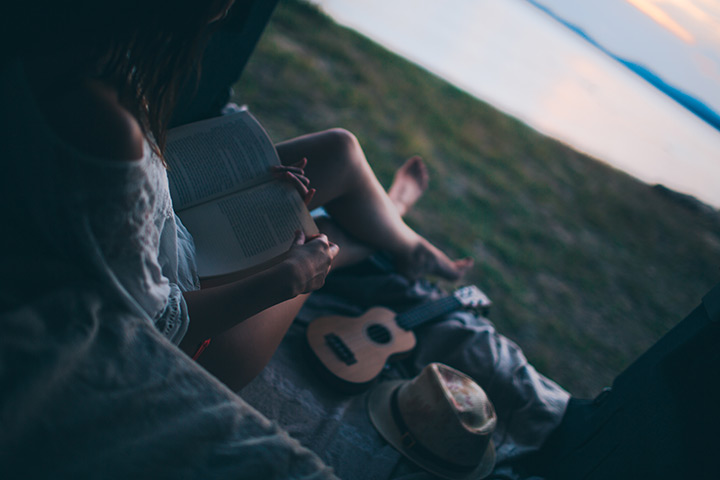 Person reading a book with a guitar