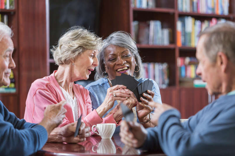 Seniors playing a table game, learn more about our senior living community in Fallbrook, California by scheduling your tour today!