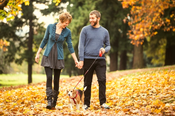 A couple smiles at they walk their dog near Spring Hollow Apartments