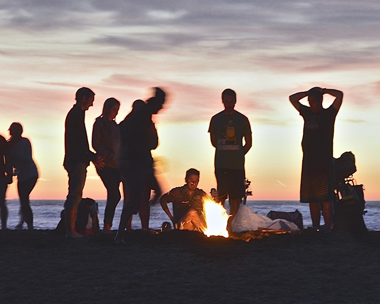 Friends and neighbors enjoying a bonfire on the beach near Pacific Shores apartments