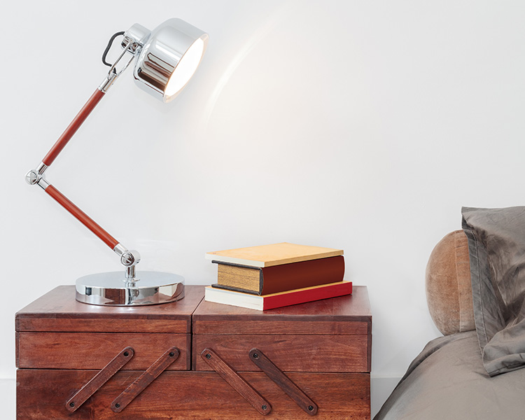 Lamp, nightstand, and bed in Pacific Shores luxury apartment bedroom