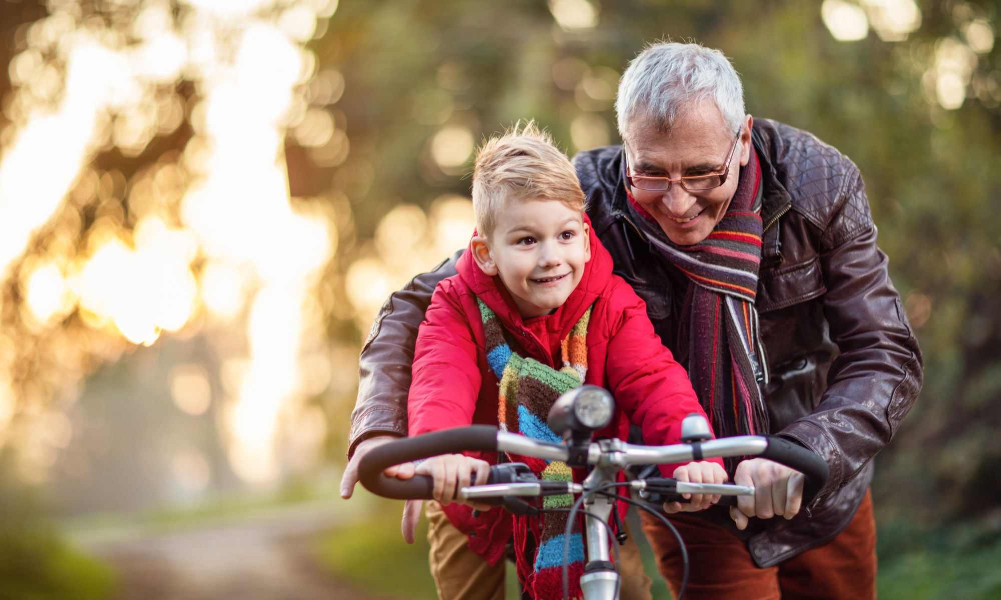 Grandfather teaching grandson to ride a bicycle at Pacifica Senior Living Millcreek