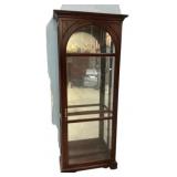 Arched curio cabinet with a walnut finish and a mi