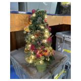Lighted Christmas holiday tree in pot with fruit