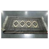 Small fringed area rug. Black and tan pattern.