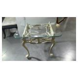 Glass top table with ornate heavy metal base, the
