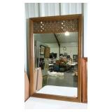 Framed mirror with lattice design at top.