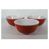Three orange Pyrex bowls