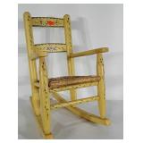 Child sized wooden rocker with woven seat.  Seat