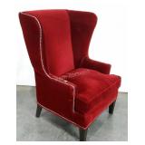 Large wingback chair in red velveteen fabric.