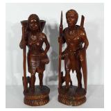 Wooden statues of man and woman, each with a dog.