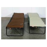 Two camping cots, one is ripped but covered by
