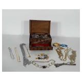 Wooden jewelry box full of jewelry and pins.