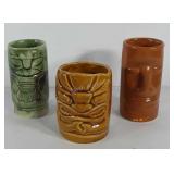 Three ceramic tiki mugs, two have fleabites on