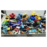 Box full of small toys, mostly cars and trucks.