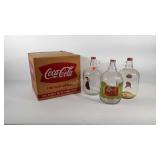 Three one gallon glass Coca-Cola jugs, all with
