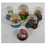 Five souvenir snow globes and one paperweight,