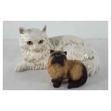 Two cat statues, one tilted "whiskers" and artist