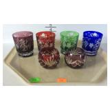 Four colorful drinking glasses and two candle