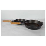 Two cast skillets with wooden handles, one m