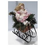 Holiday decor, porcelain doll on sled with pine