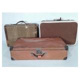 Three suitcases, all show wear