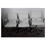 Three white vinyl office chairs, all have scuffs