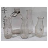 Five glass milk bottles in various sizes, one has