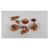 Six small copper molds and a teapot cap