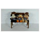 Three stuffed friends sitting on wooden bench.