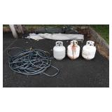 Three empty propane tanks and garden hose