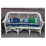Wicker patio sofa with green and blue cushions,