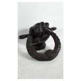 Metal door knocker in the shape of a fist.
