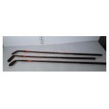 3 wooden shaft golf clubs. One is a putter.