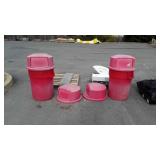 Two red rubbermaid poly trashcans with lids and
