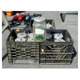 3 plastic milk crates filled with glass canister